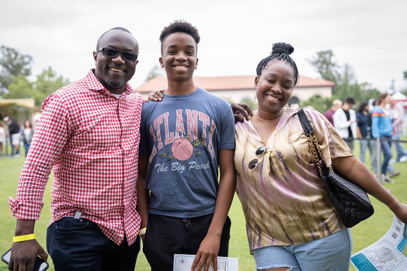 A student and their family pose with their arms around each other, smiling.